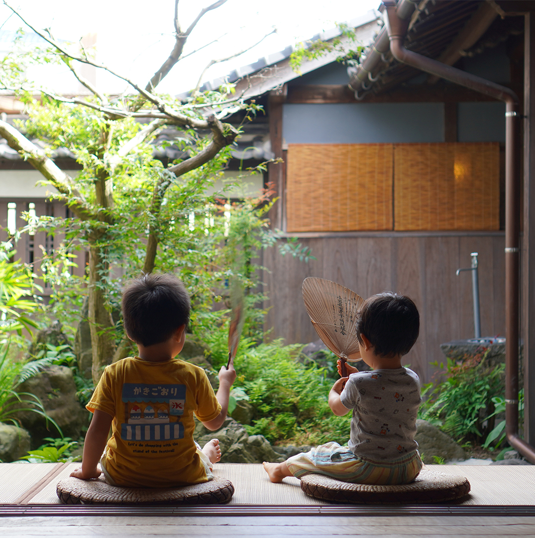 塩屋の縁側にに男の子2人が座っている様子